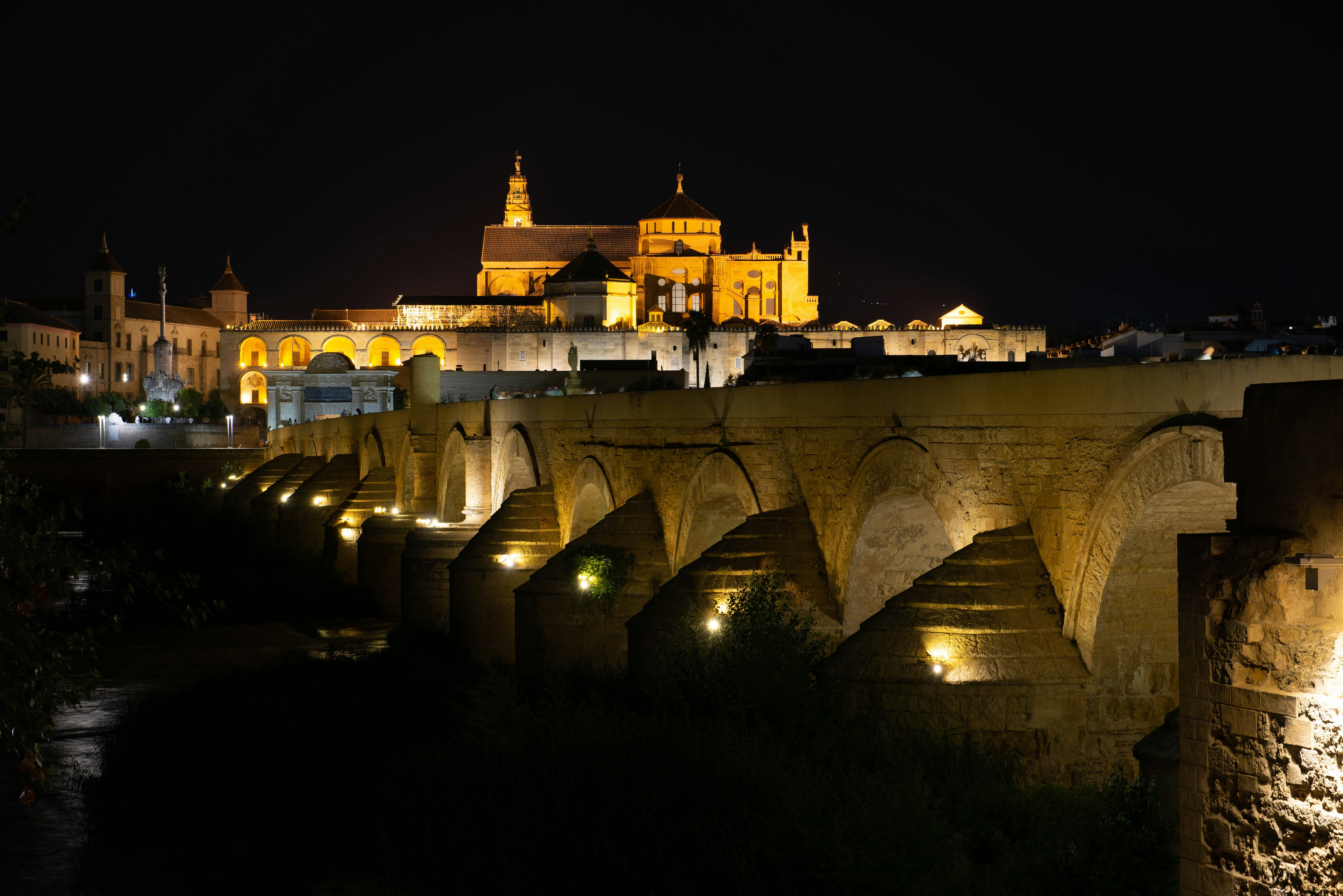 A lit-up bridge leads to a beautiful building.