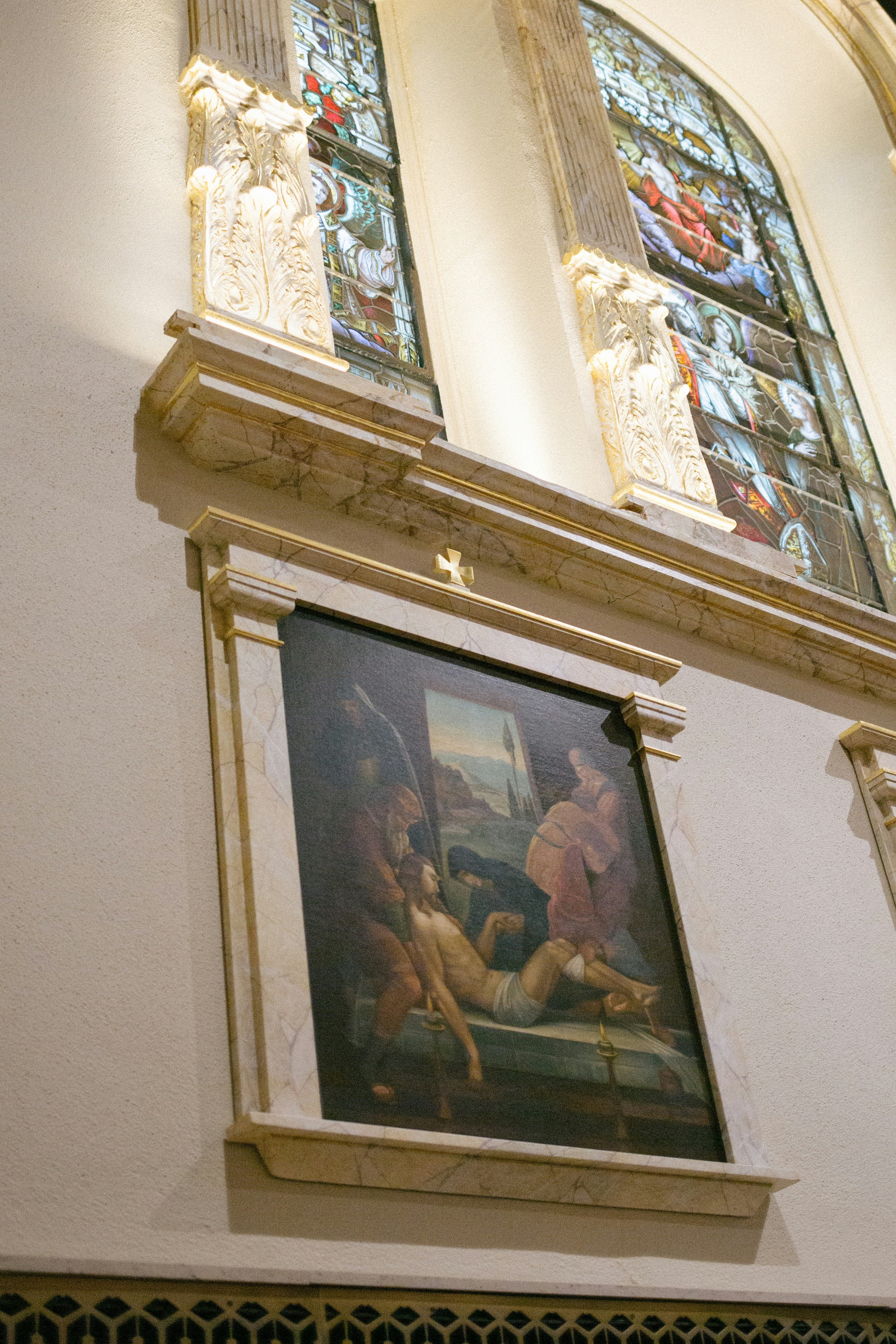 Un cuadro cuelga bajo una vidriera.