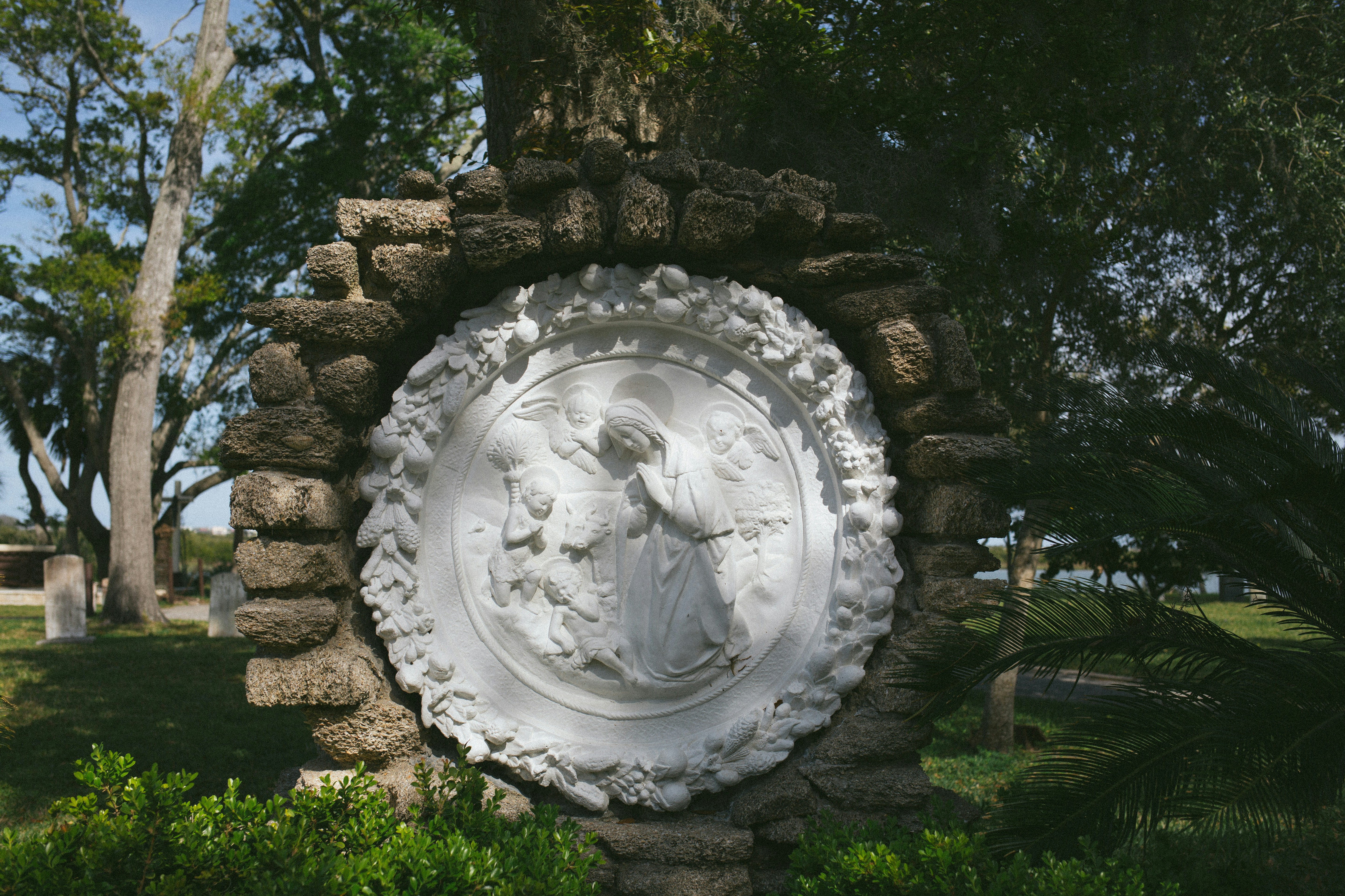 Escultura de piedra con un ángel y follaje.