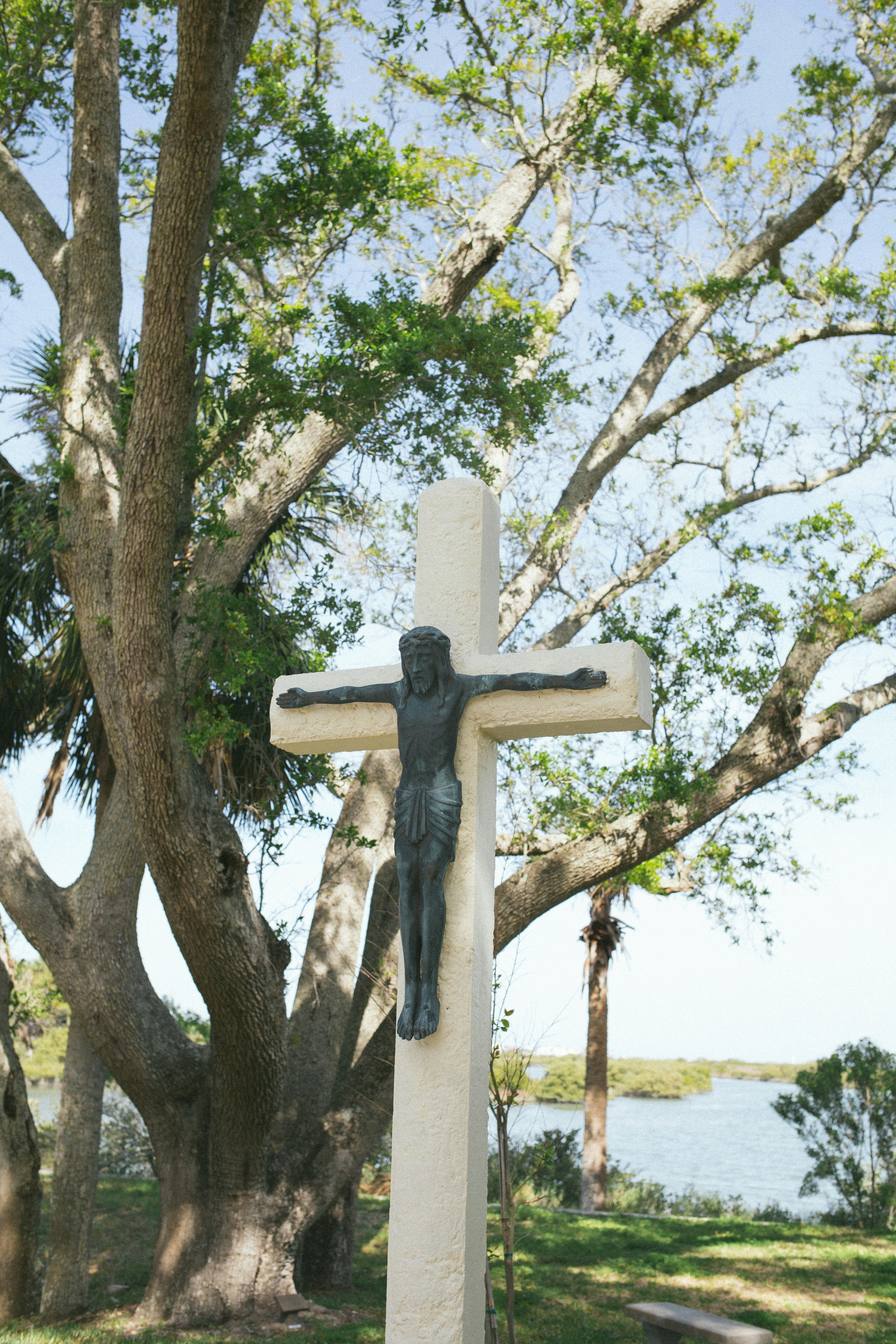 Un crucifijo se encuentra cerca de un árbol y el agua.