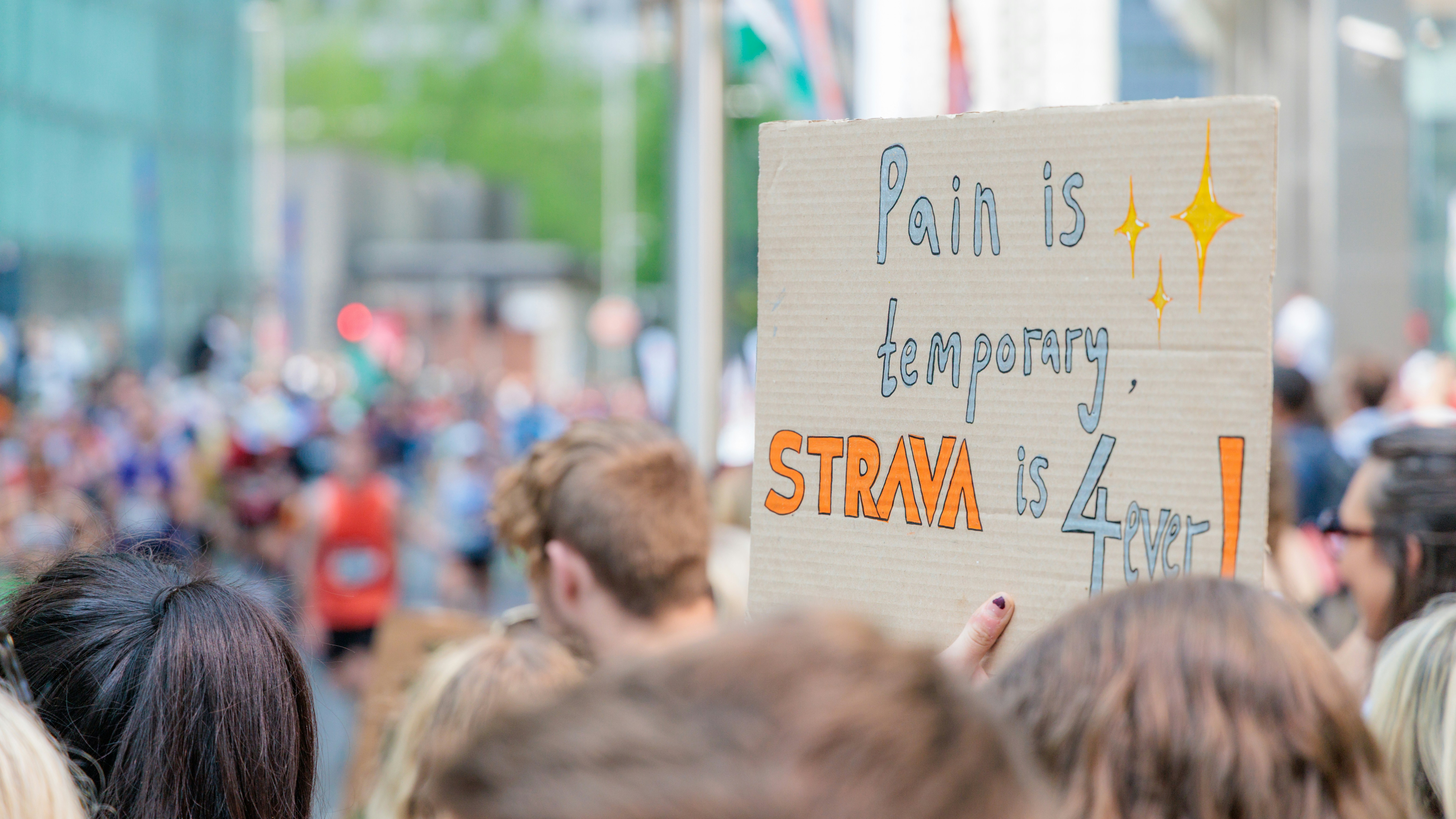 A spectator holds up a sign at a running race.