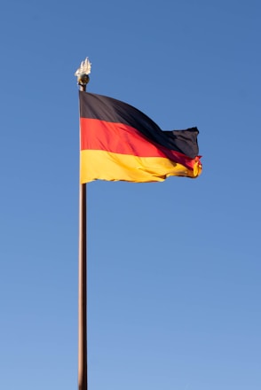 The german flag is waving against a blue sky.