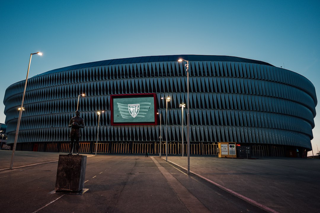 San Mamés stadium in Bilbao at dusk with the Athletic Club crest lit on the facade