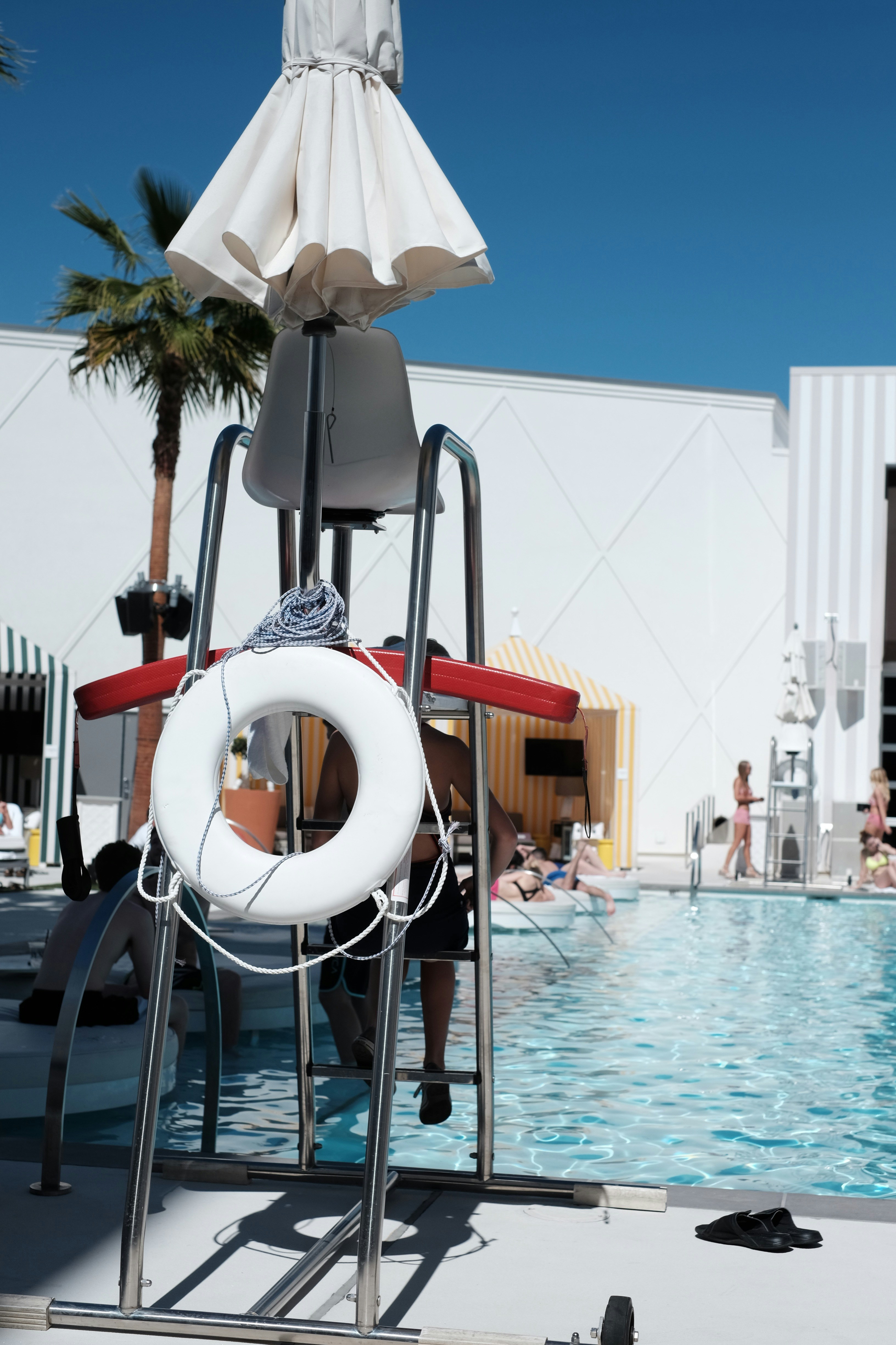 Lifeguard stand at the pool with people swimming.