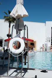 Lifeguard stand at the pool with people swimming.