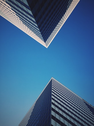 Two skyscrapers meet at the blue sky.