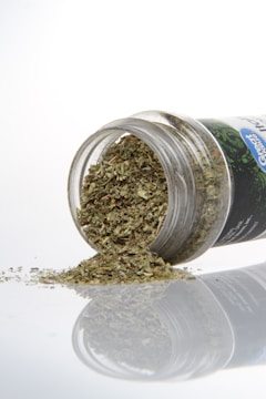 Dried herbs spilling from a clear container.