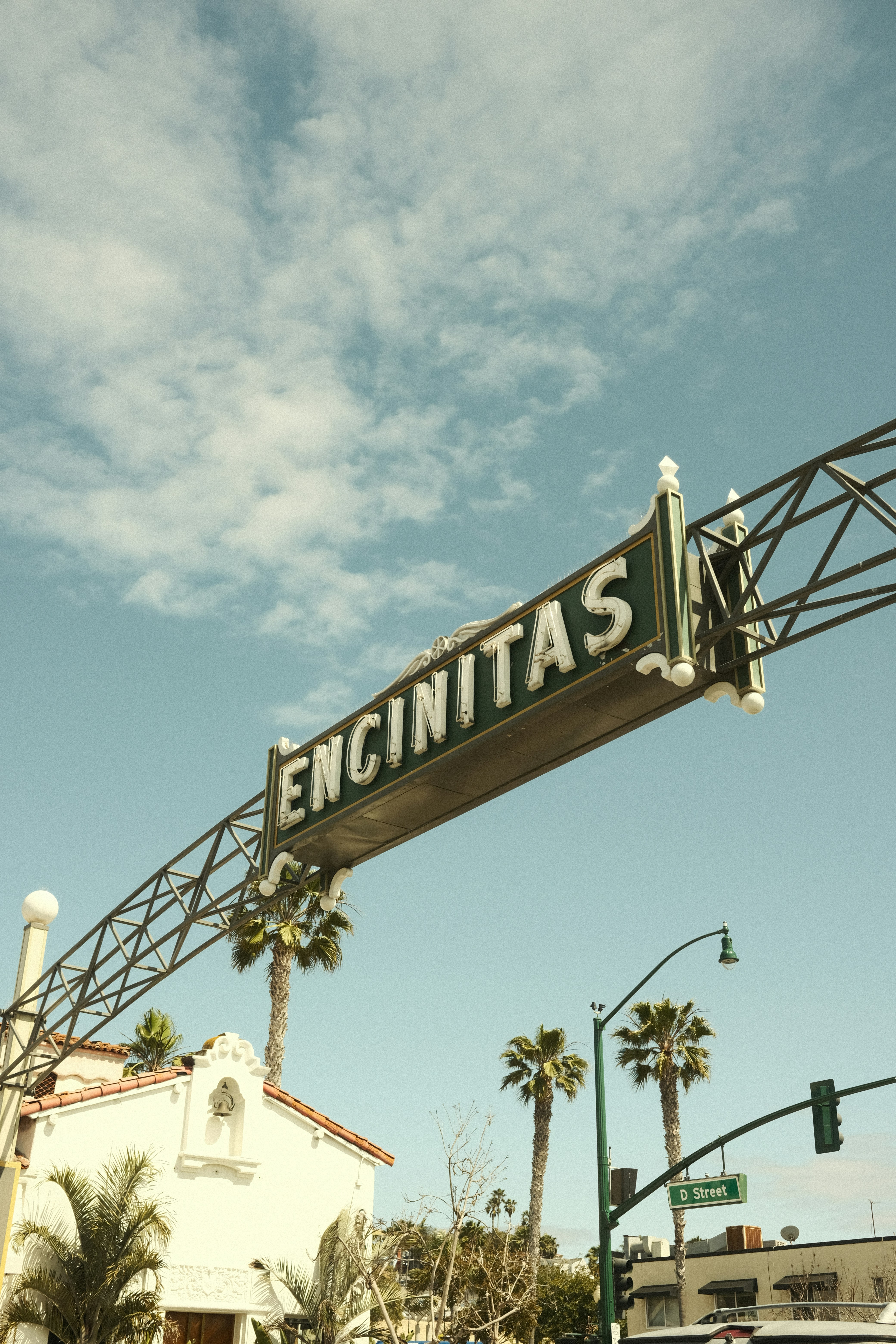 The encinitas sign hangs under a sunny sky.