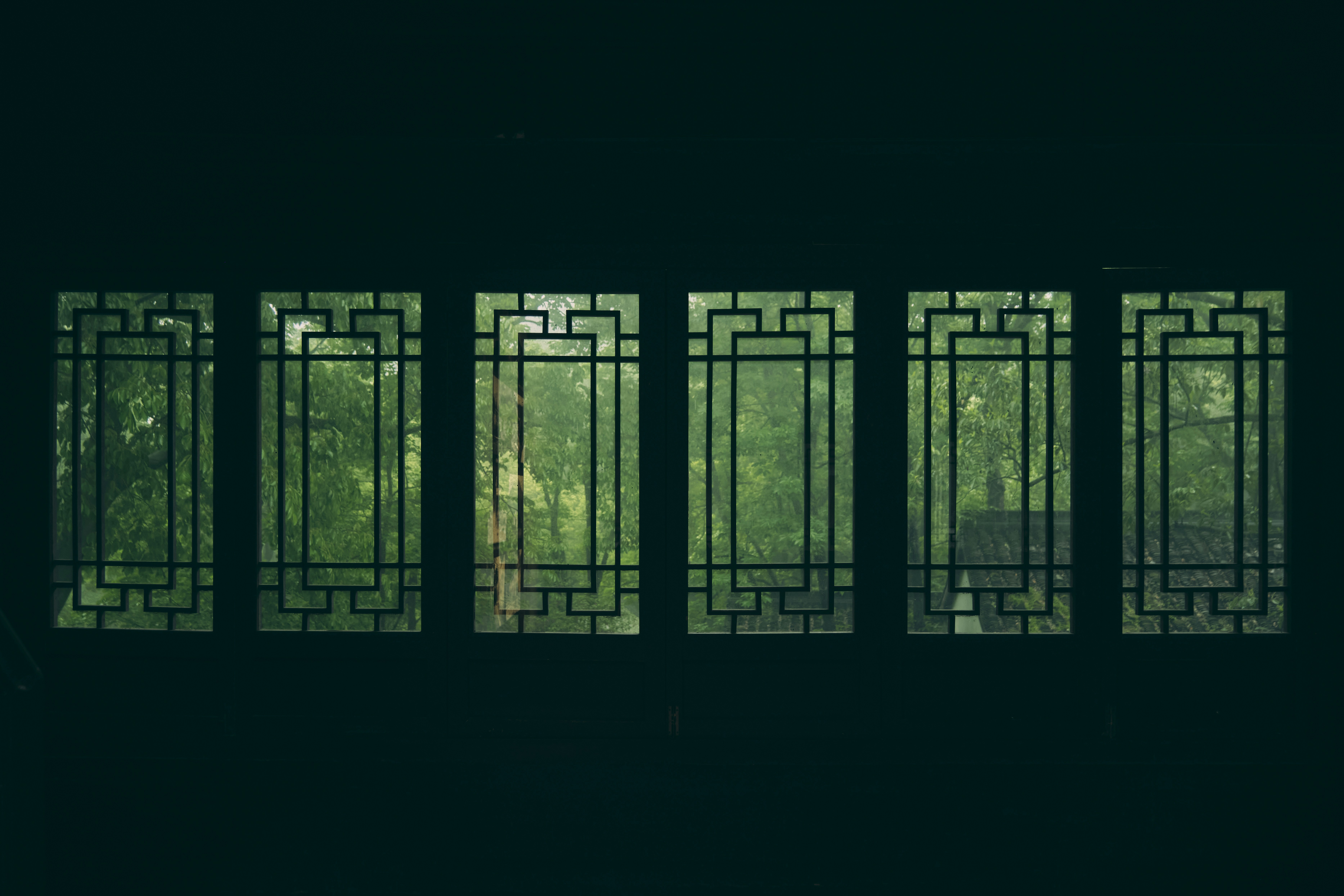 Six rectangular windows look out onto a lush green garden.