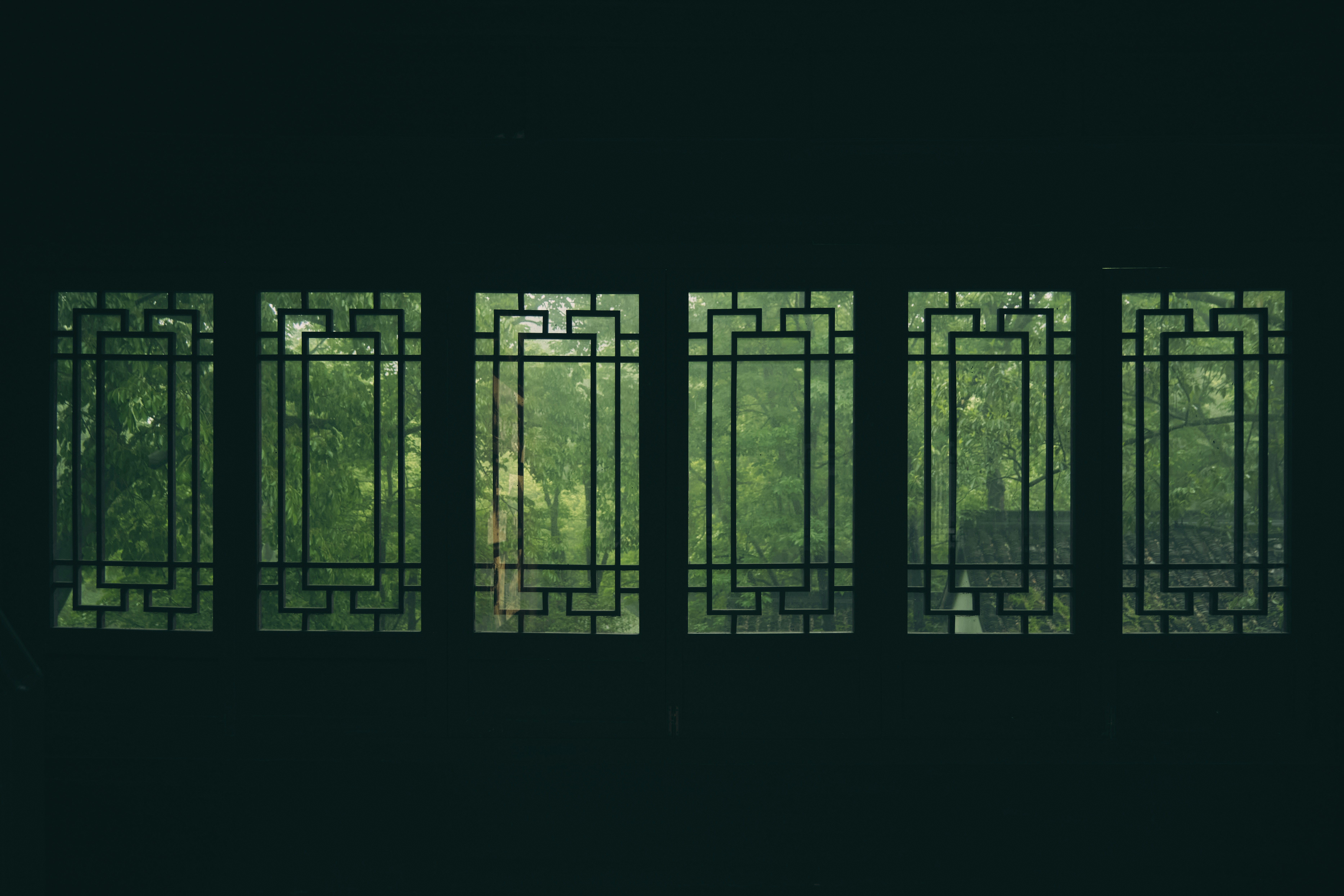 Six windows provide a view of green trees.