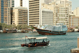 Boats navigate the water with tall buildings behind.