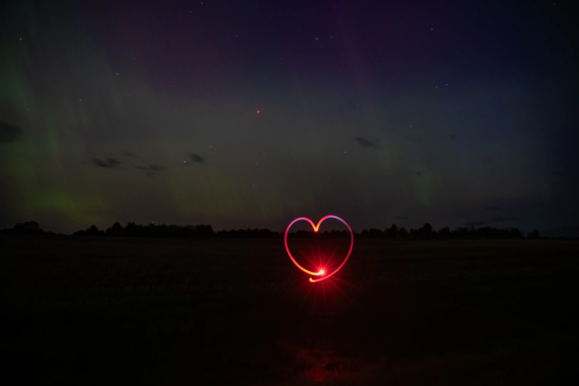 A red heart is drawn in the dark night.