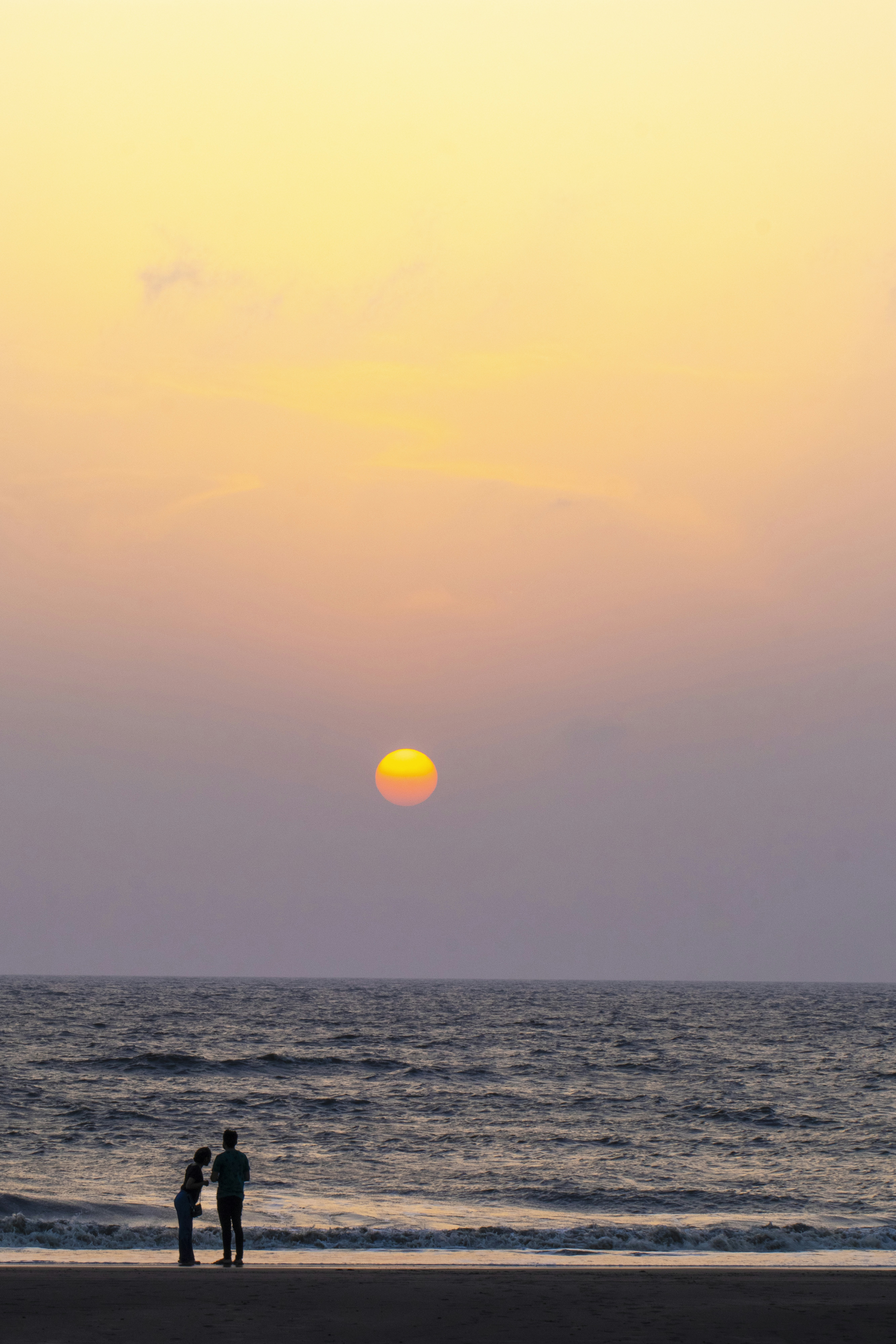 Couple watches sunset on the beach.