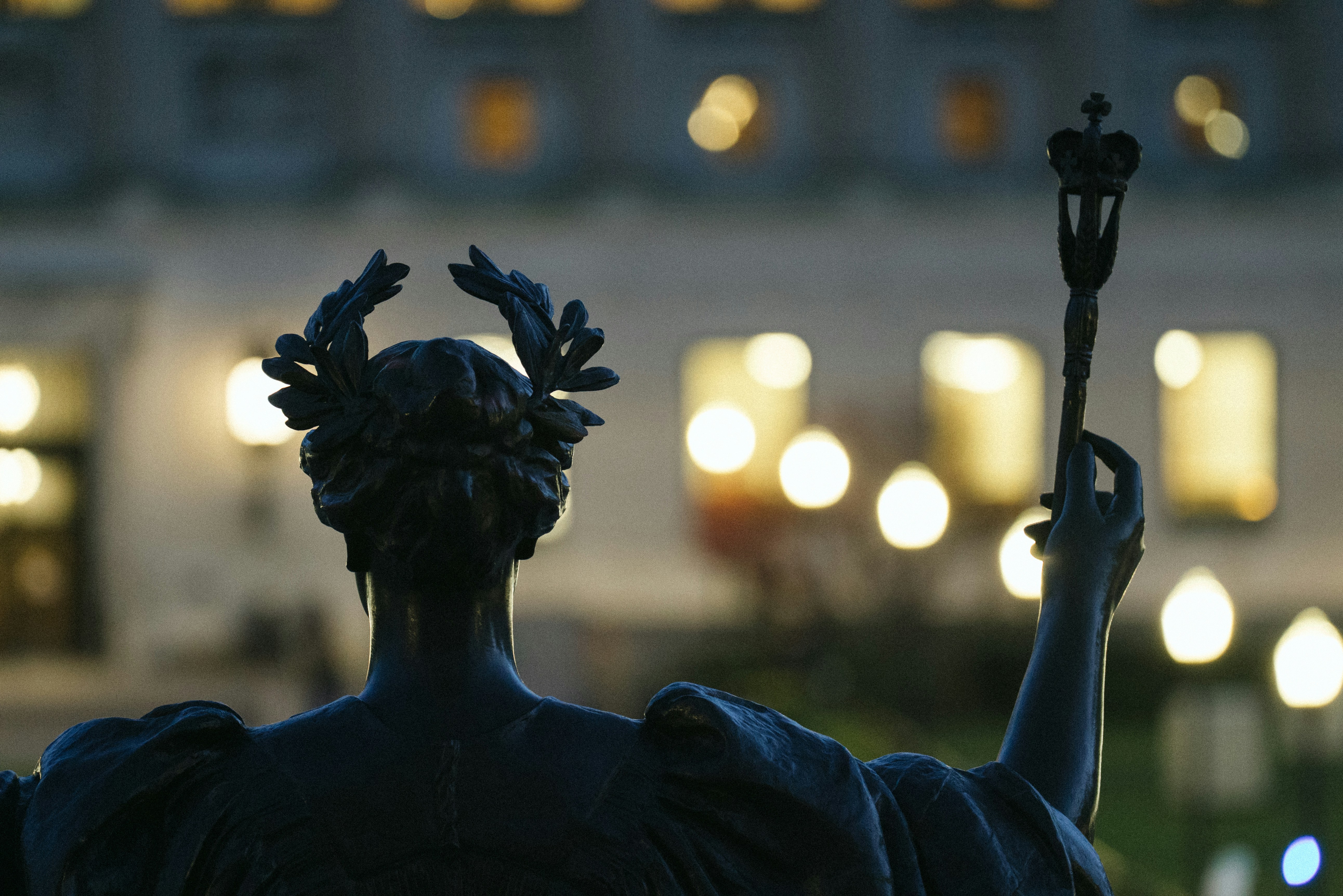 A statue faces away with a crowned scepter.