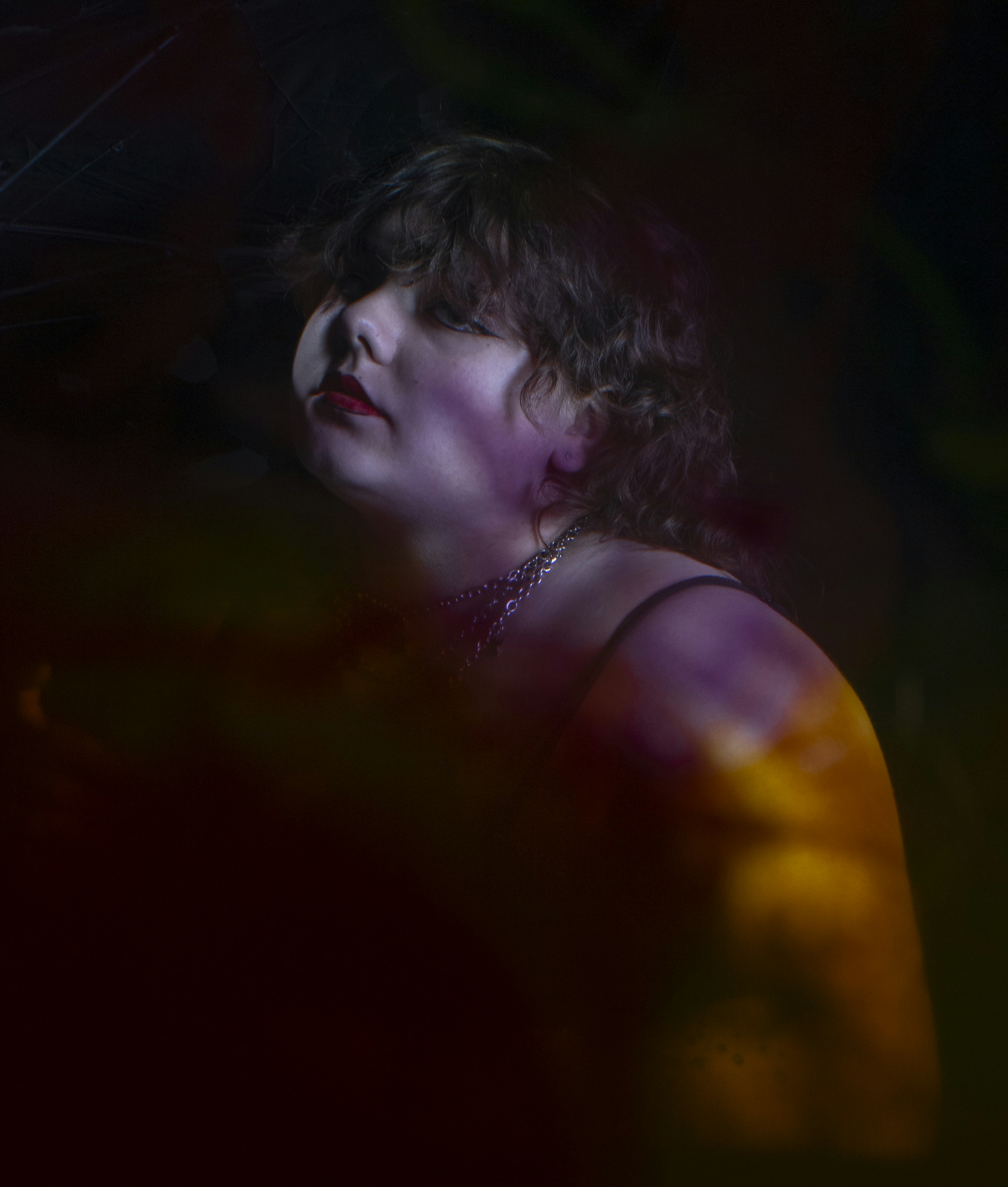 Uma mulher olha para cima em uma iluminação dramática e colorida.