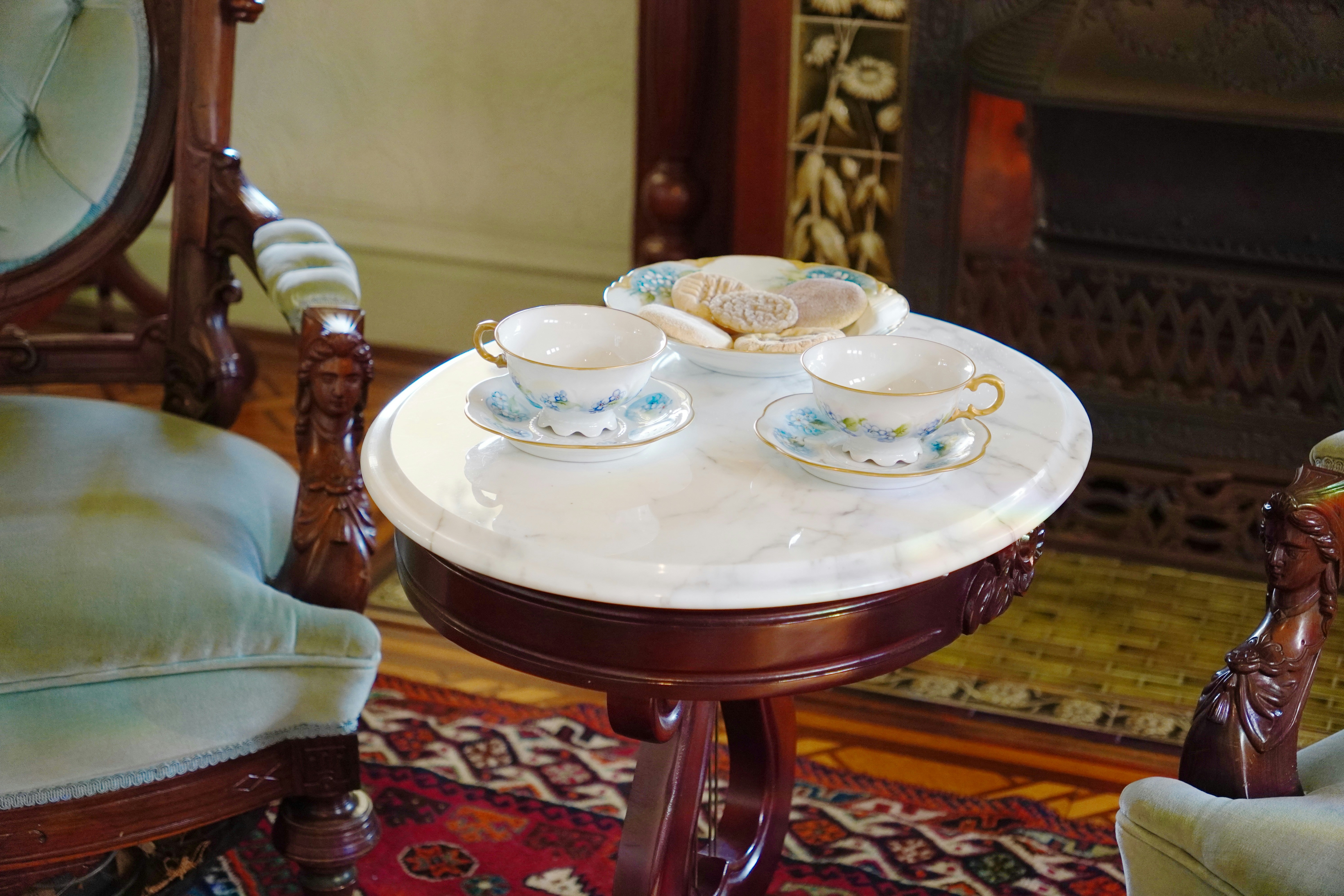 Tea cups and cookies sit on a small table.