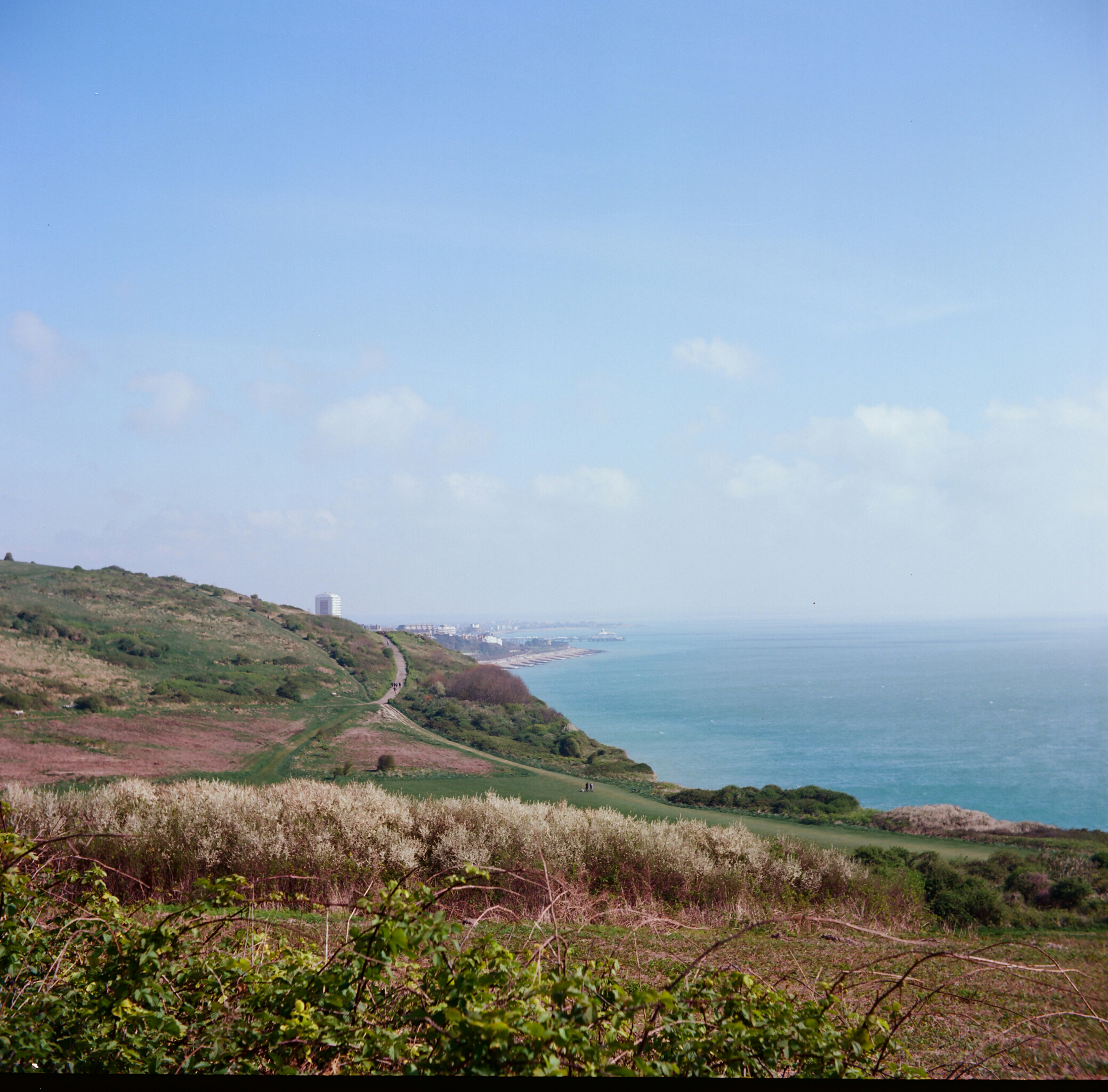 A coastal landscape with ocean, hills, and clear sky
