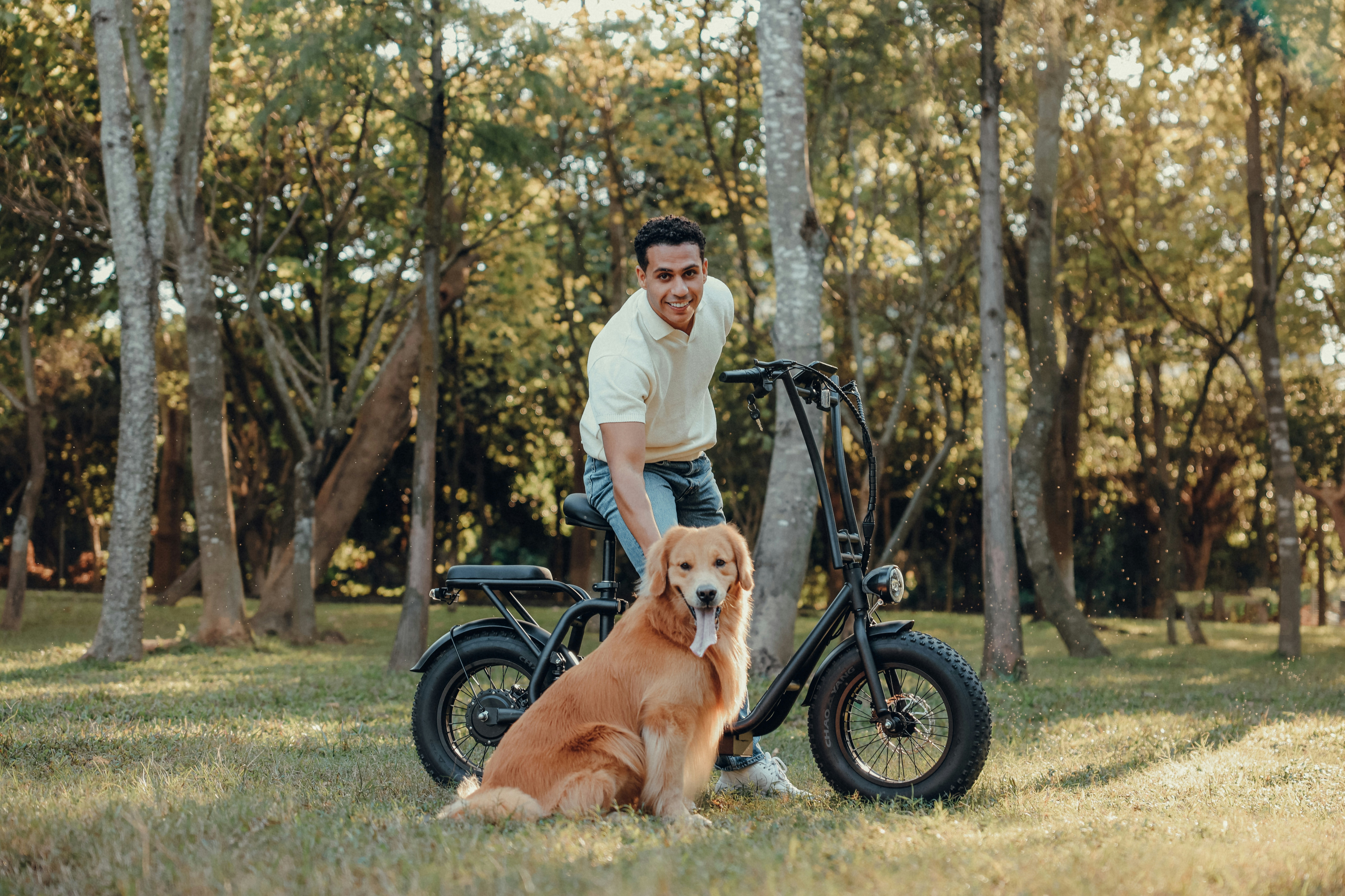 Man and dog pose by a bike in a park.