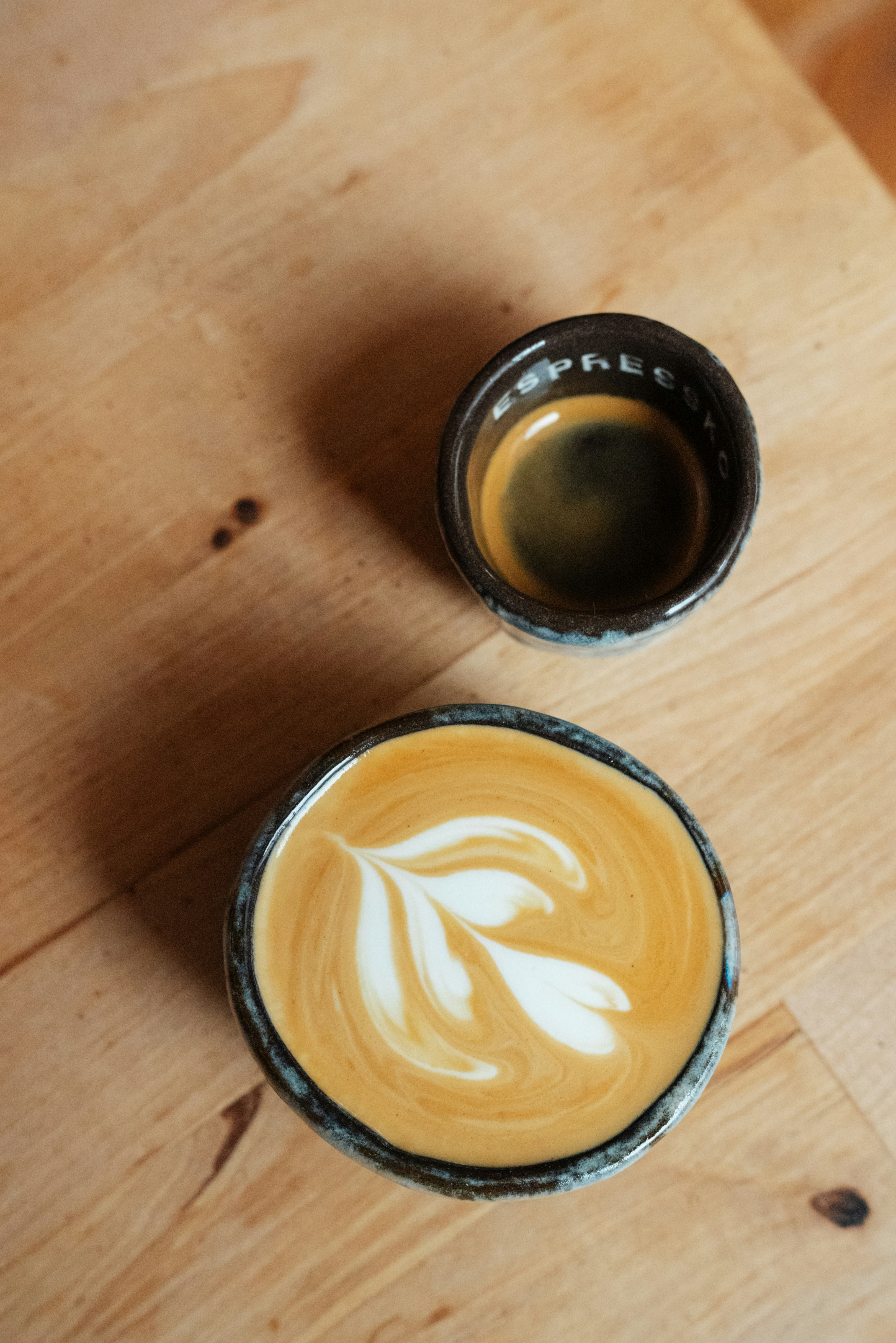Espresso and latte art on a wooden surface.