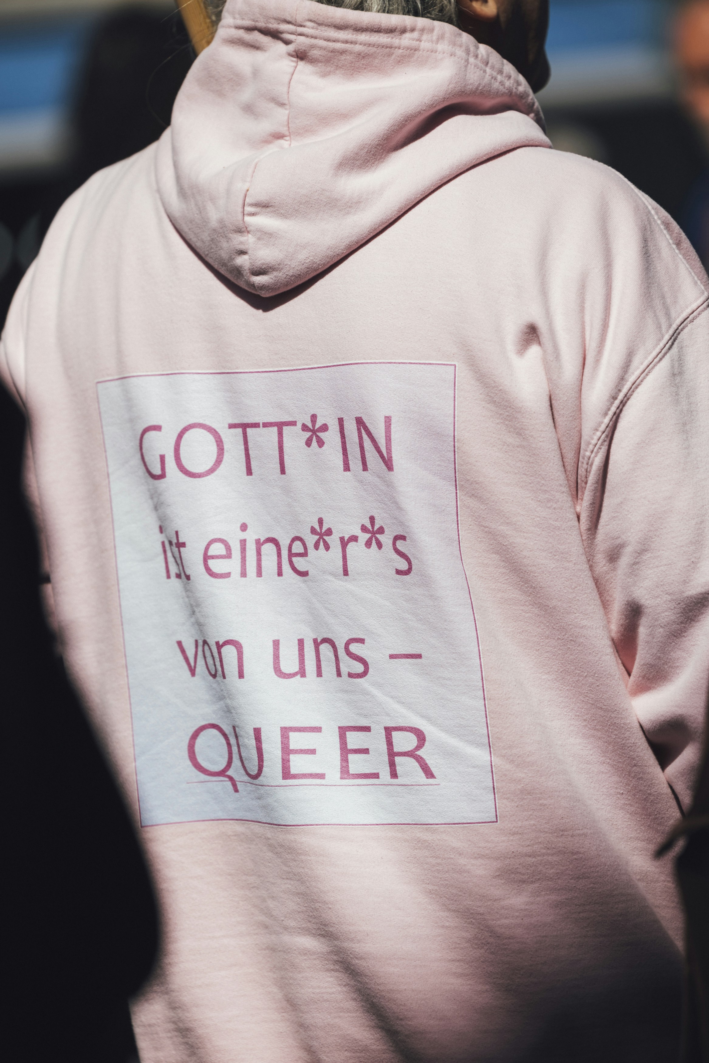 A person wears a hoodie with a queer message.
