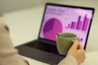 Person working on a laptop with a cup of coffee.