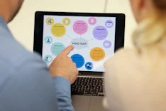 People are looking at a mind map on a laptop screen.