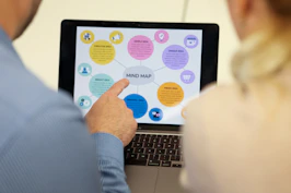 People are looking at a mind map on a laptop screen.