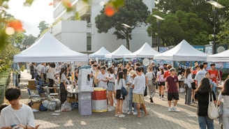 People browse and enjoy a market under tents.