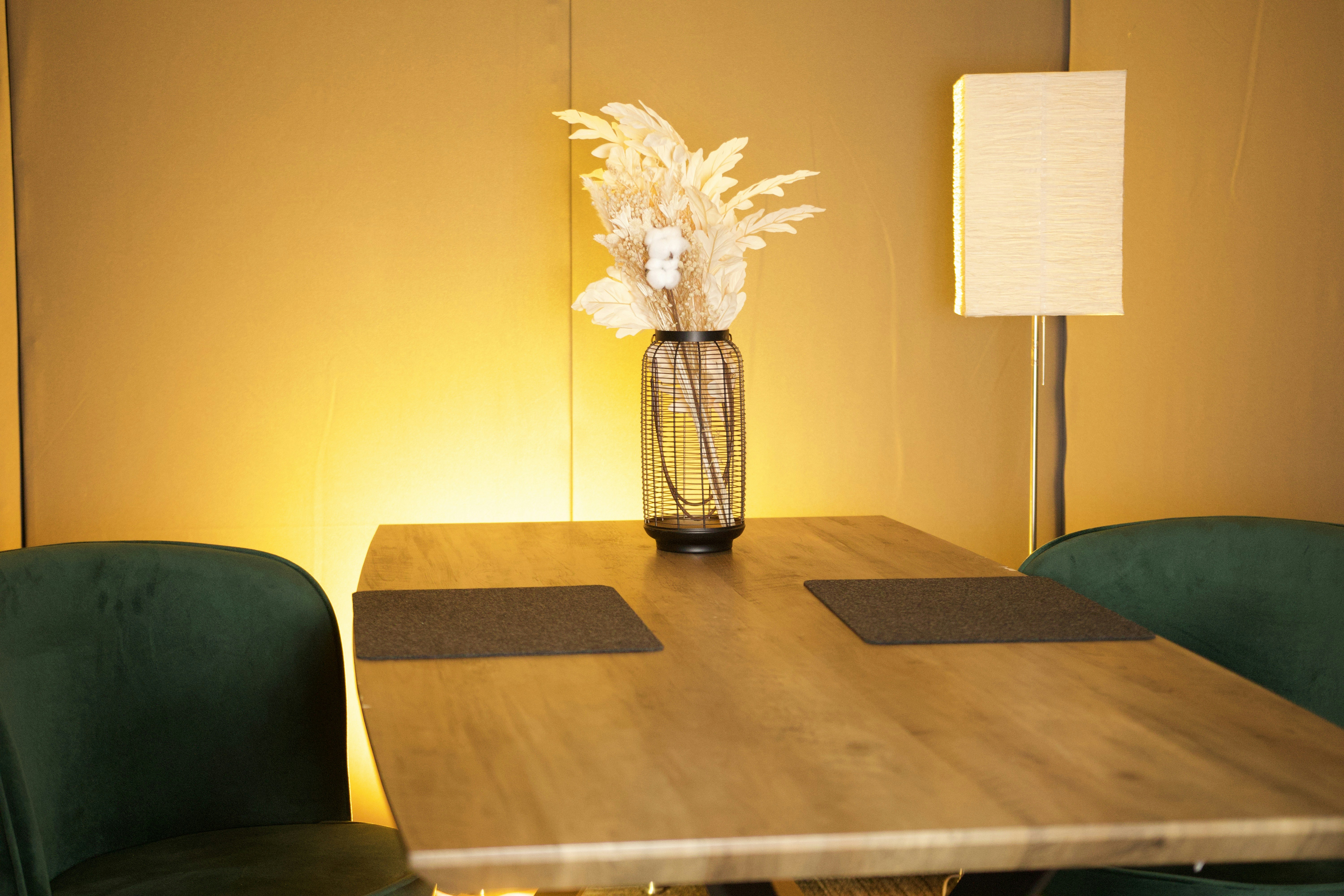 A wooden table with flowers and green chairs.