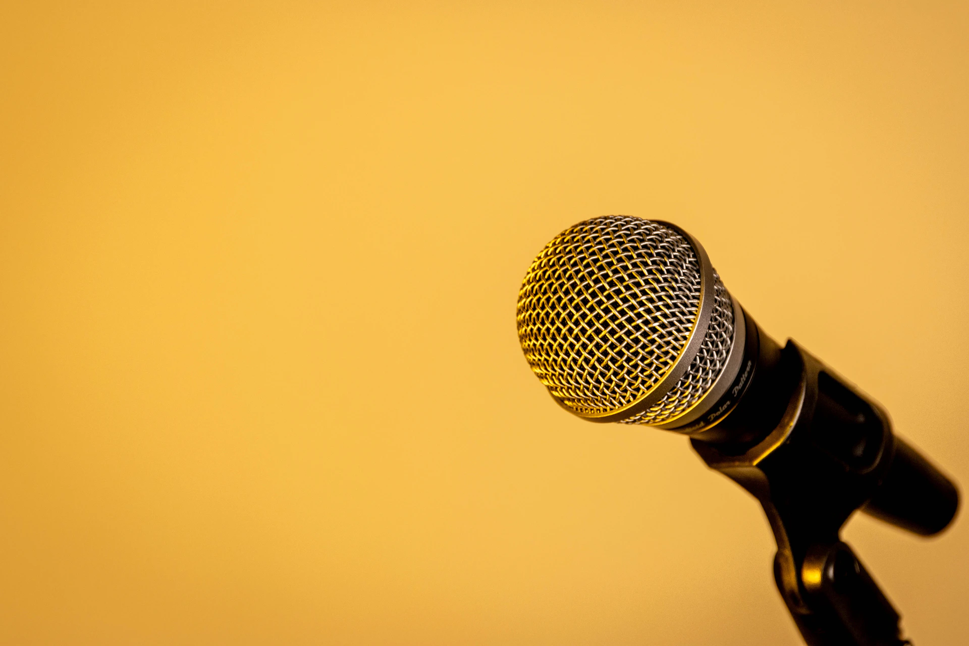 A microphone on a stand against a yellow background.