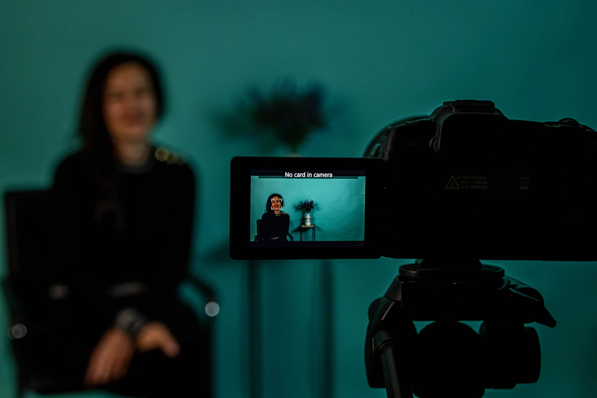Camera LCD screen in sharp focus during a filming setup, with the subject blurred in the background, illustrating handheld video and vlog recording