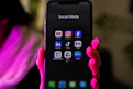 A smartphone displays social media app icons.