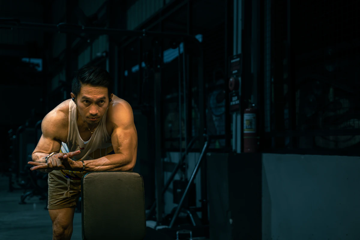 Muscular man resting between sets at the gym, illustrating the recovery and lean-mass goals men pursue with hexarelin peptide therapy.