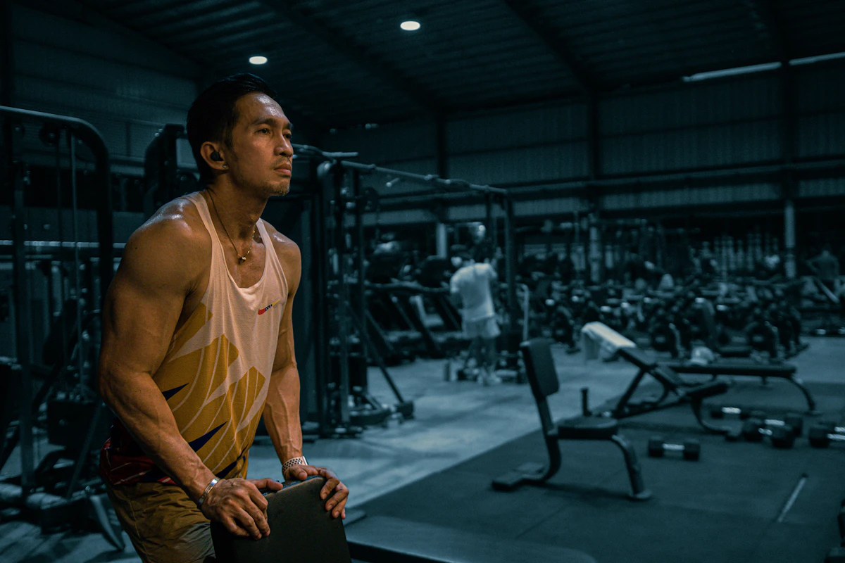 Man training with weights at the gym, tracking his progress over time, illustrating the gradual timeline of peptide therapy results.