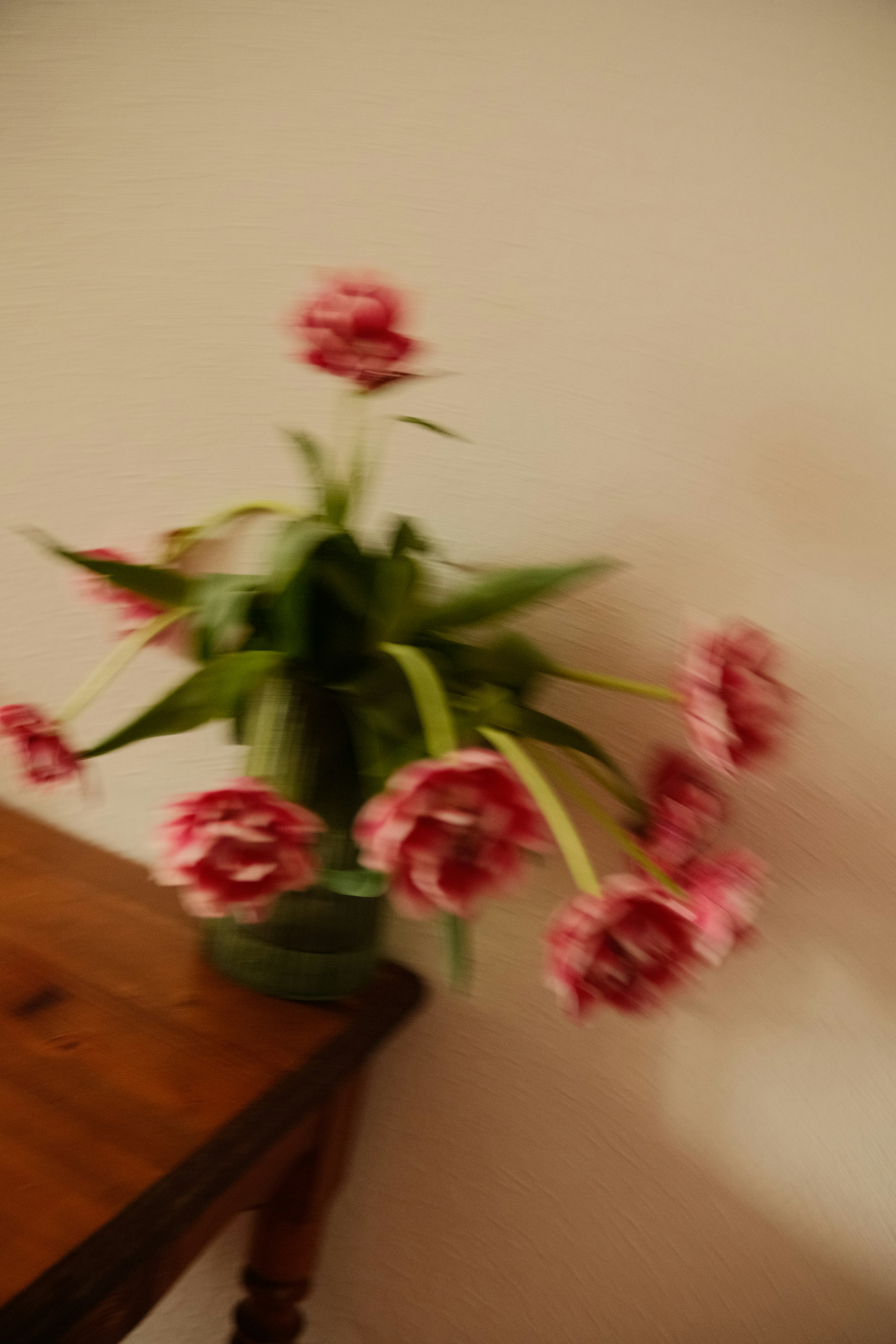 Blurred flowers in a vase on a wooden table.