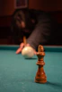 A chess king stands on a pool table.