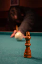 A chess king stands on a pool table.