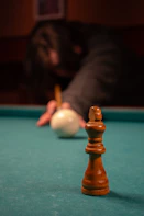 A chess king stands on a pool table.
