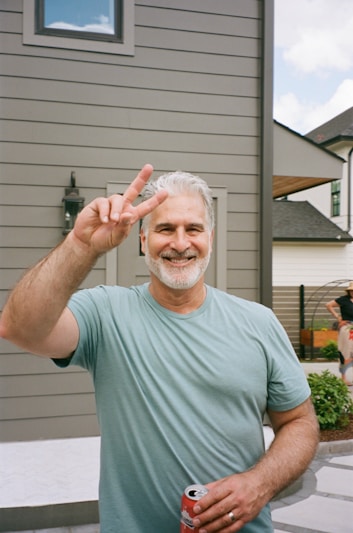 Man gives peace sign, smiling brightly.