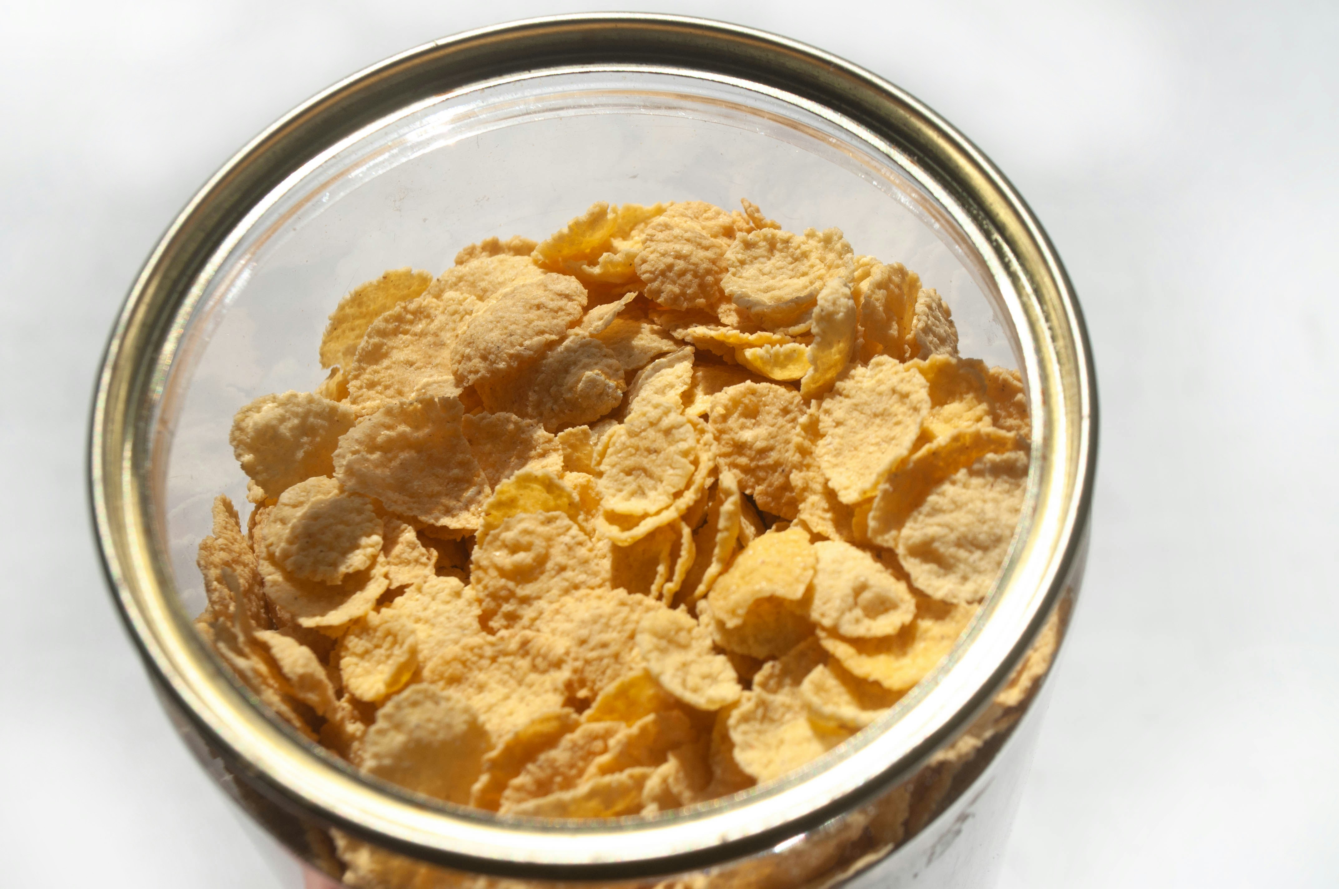 Top view corn flakes in a bowl on white background. Cereal breakfast in a plastic container