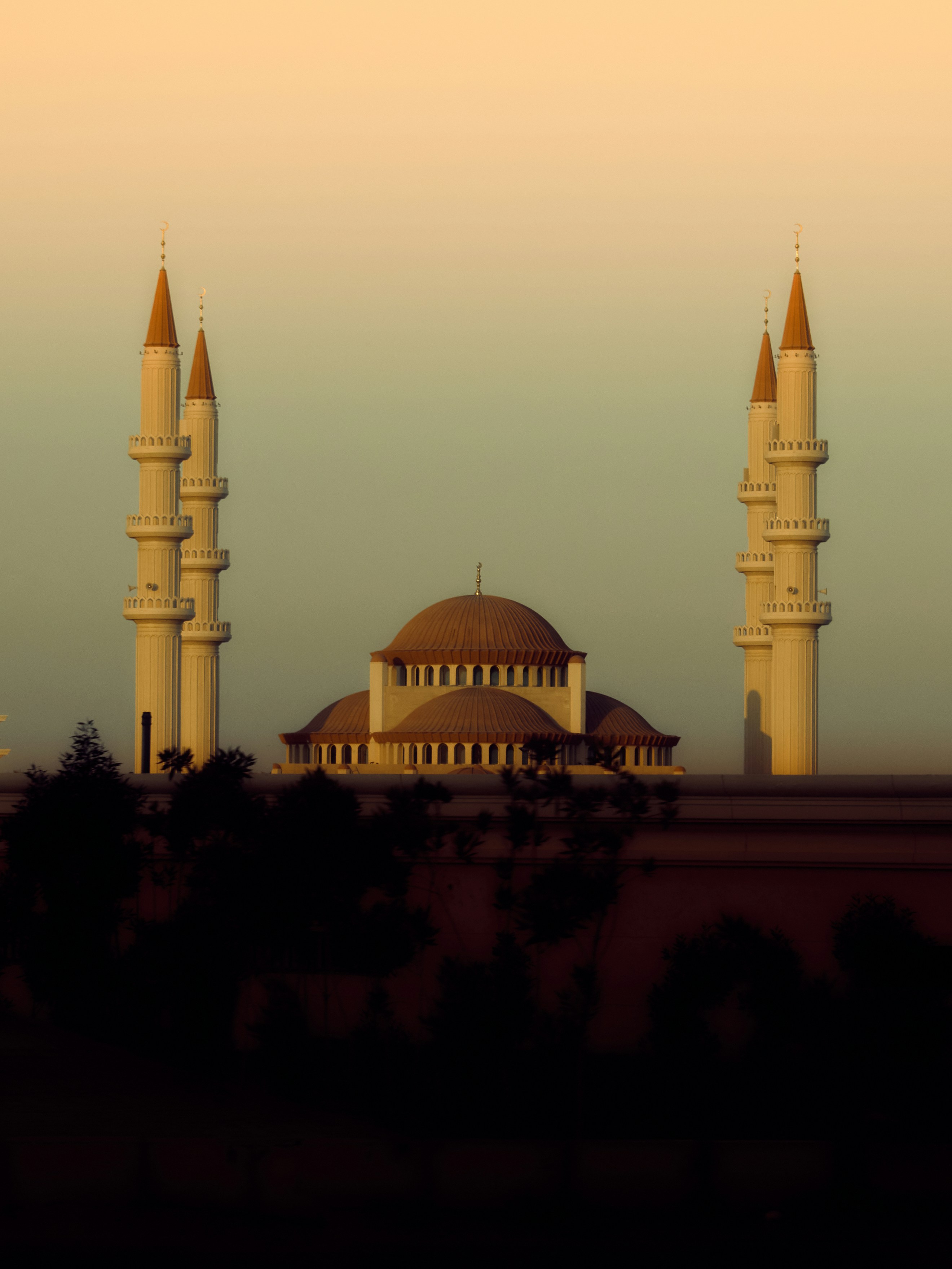 A mosque with four minarets at sunset.