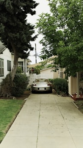 A silver car is parked on a long driveway.