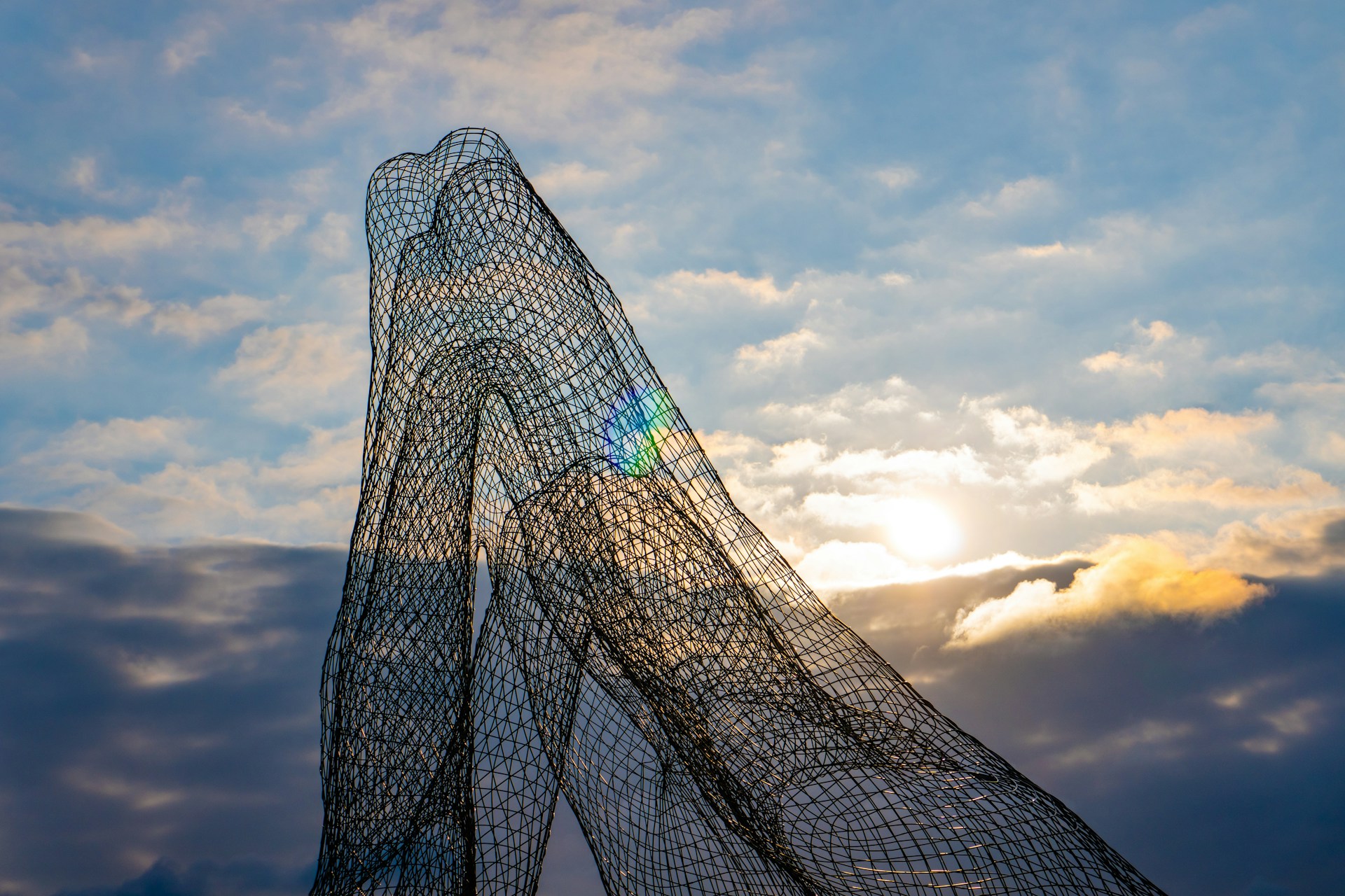 Abstract sculpture stands against a cloudy sky.