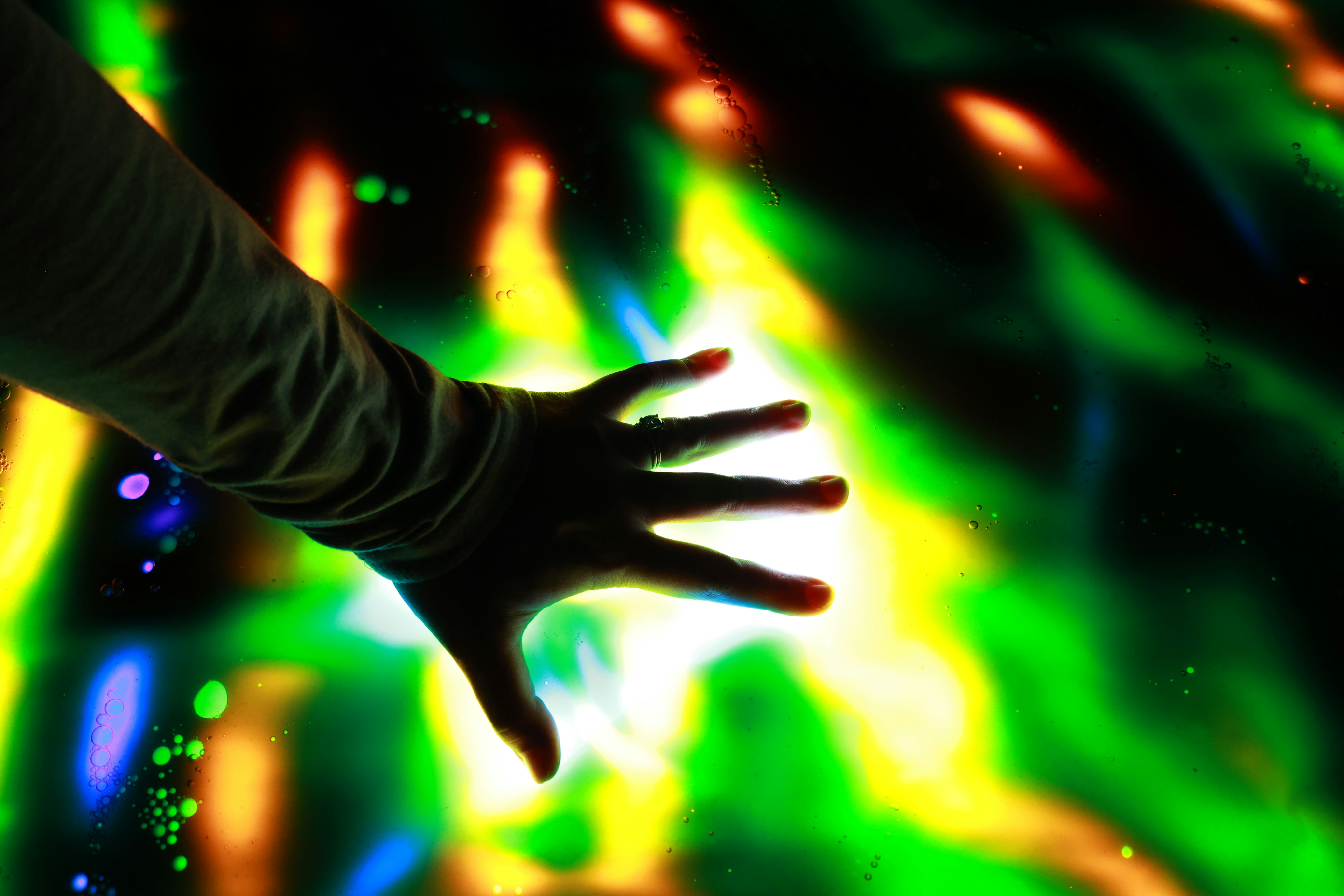 A hand touches colorful lights.