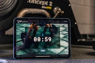 Tablet displays a timer, with workout equipment in background.