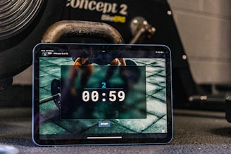 Tablet displays a timer, with workout equipment in background.