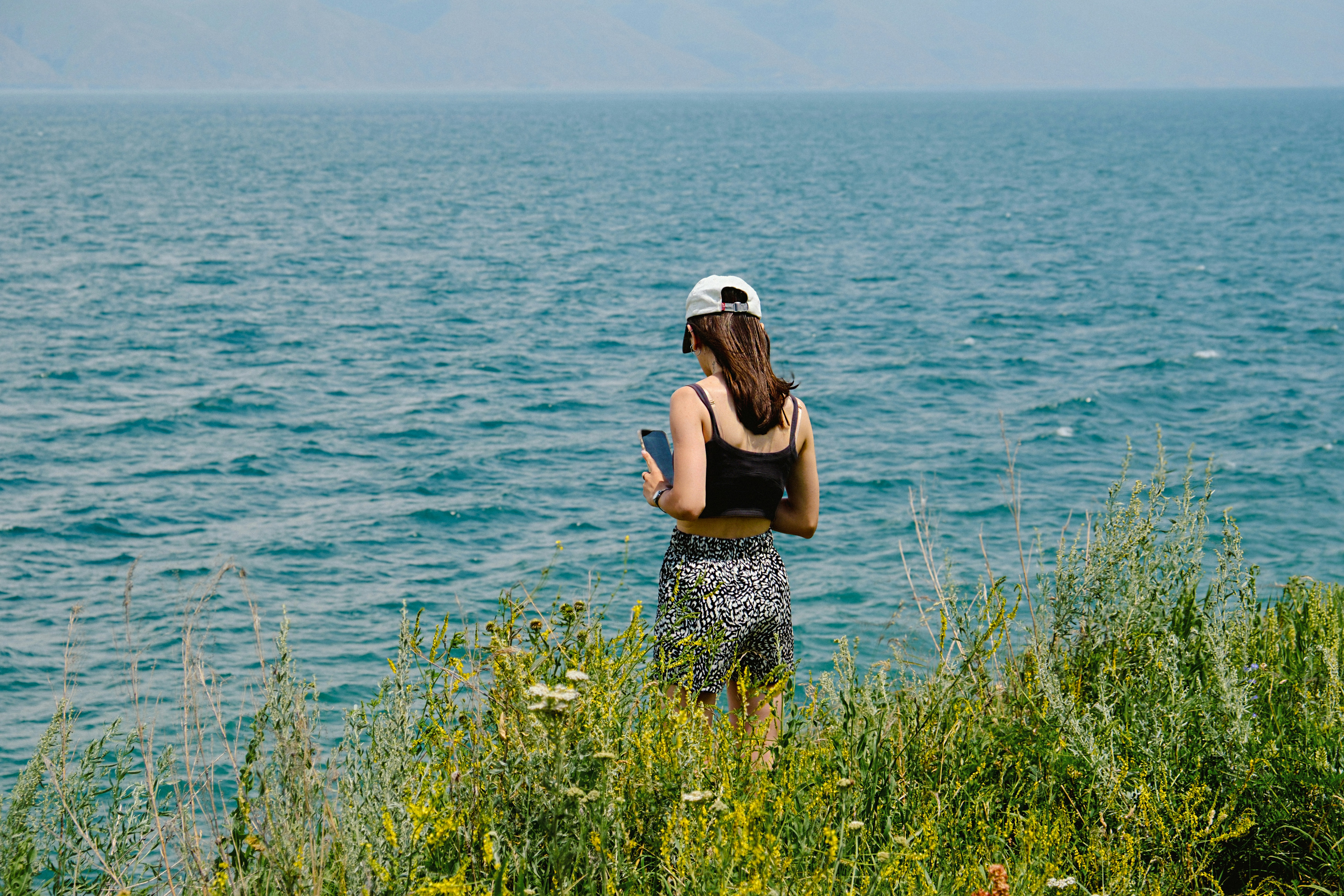 A woman stands, gazing at the tranquil sea.