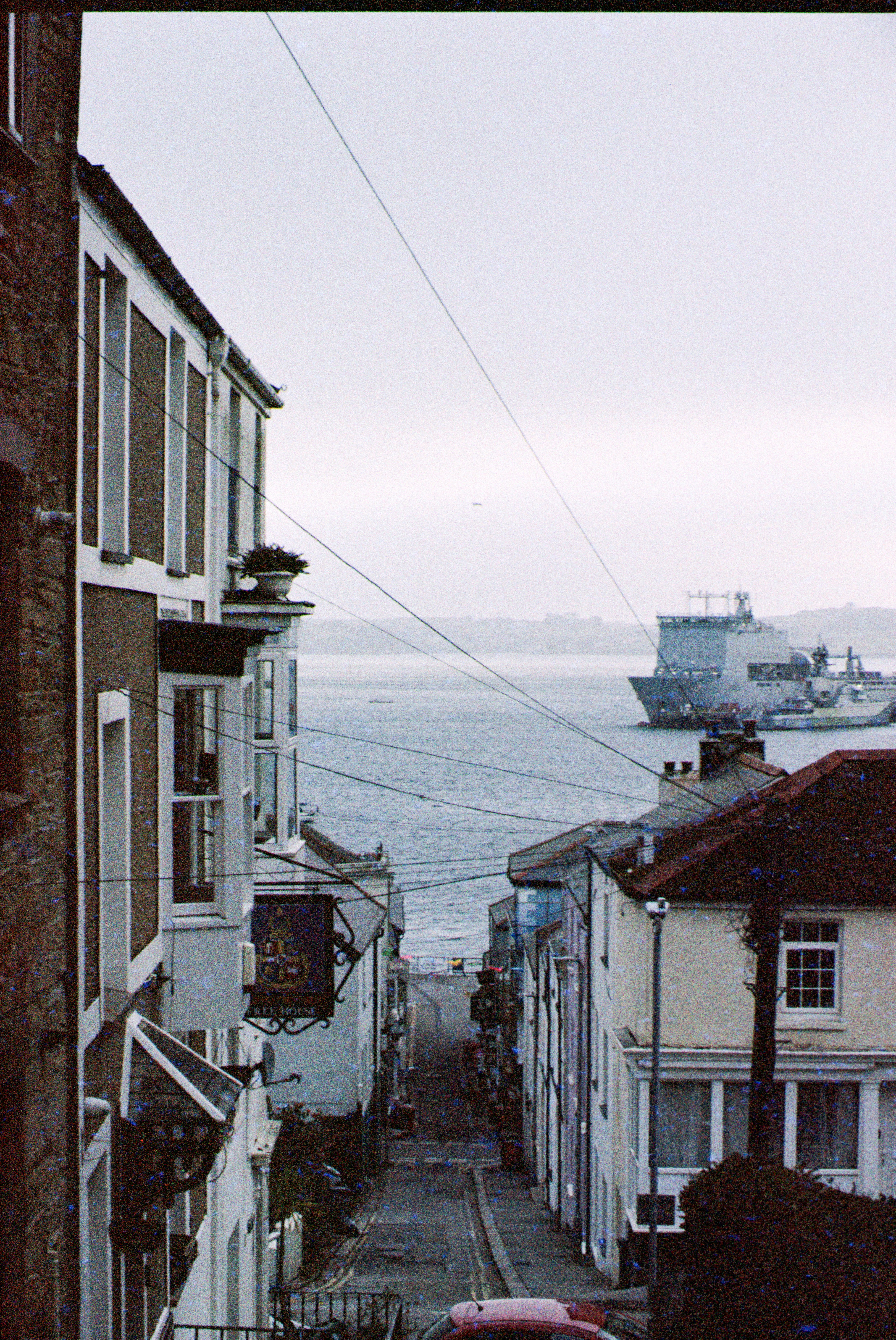 A narrow street leads to a calm sea.
