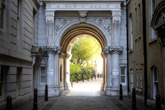 An ornate archway leads to a sunlit path.