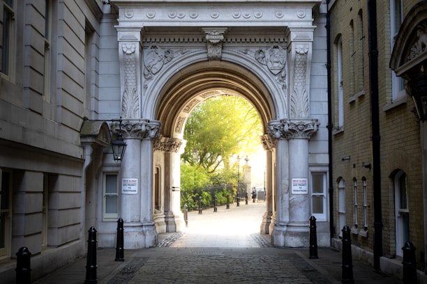 An ornate archway leads to a sunlit path.
